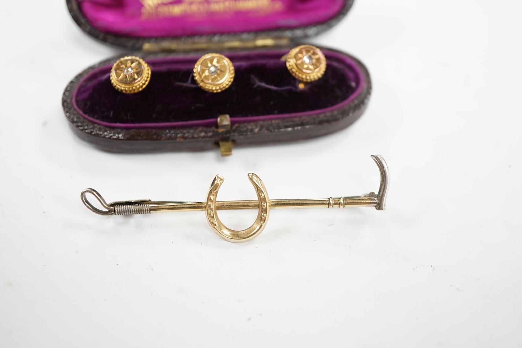 An Edwardian cased set of three 9ct and rose cut diamond set dress studs and a 9ct and silver riding crop and horseshoe bar brooch. Condition - fair